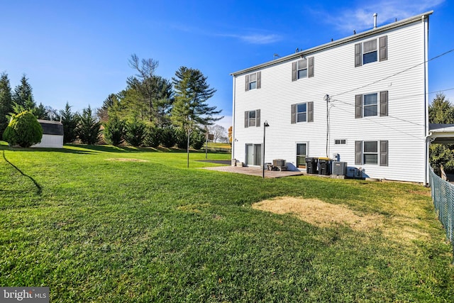 back of property with central air condition unit, a patio area, and a yard