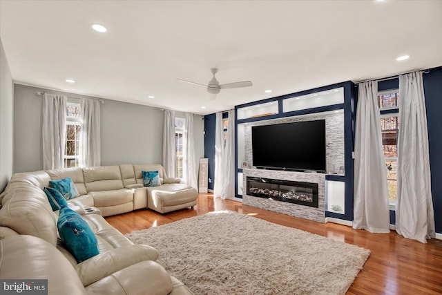 living room with hardwood / wood-style floors, ceiling fan, and a fireplace