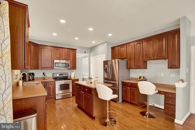 kitchen with sink, a center island, stainless steel appliances, a breakfast bar, and light wood-type flooring