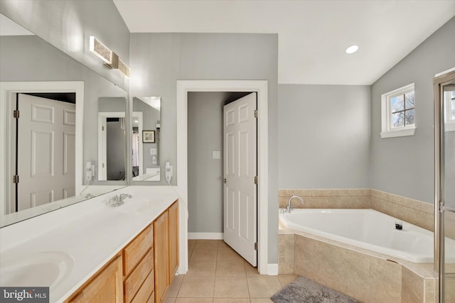 bathroom featuring tile patterned flooring, vanity, lofted ceiling, and tiled bath