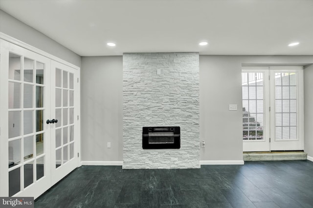 unfurnished living room featuring a stone fireplace, french doors, dark wood-type flooring, and heating unit