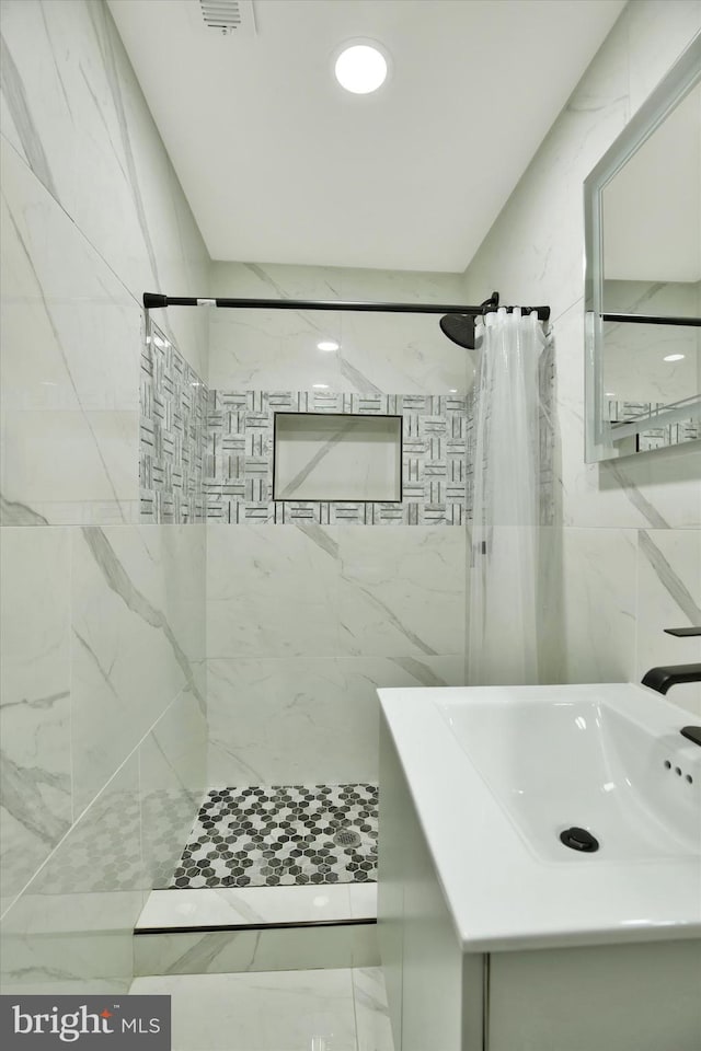 bathroom featuring a shower with curtain, sink, and tile walls