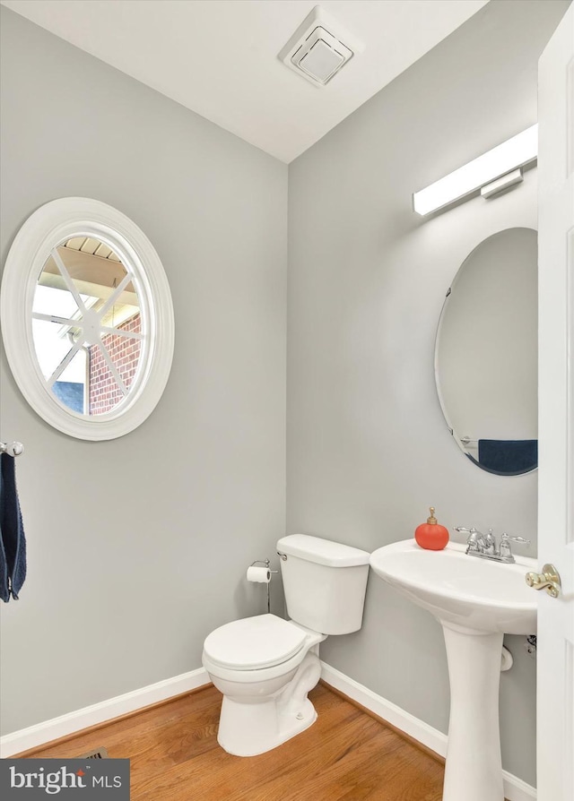 bathroom with toilet, wood-type flooring, and sink