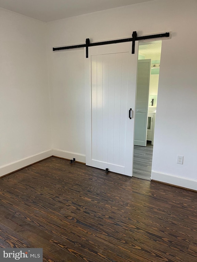 spare room with a barn door and dark hardwood / wood-style flooring