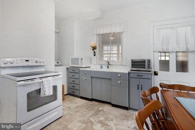 kitchen with gray cabinetry, white appliances, a healthy amount of sunlight, and sink