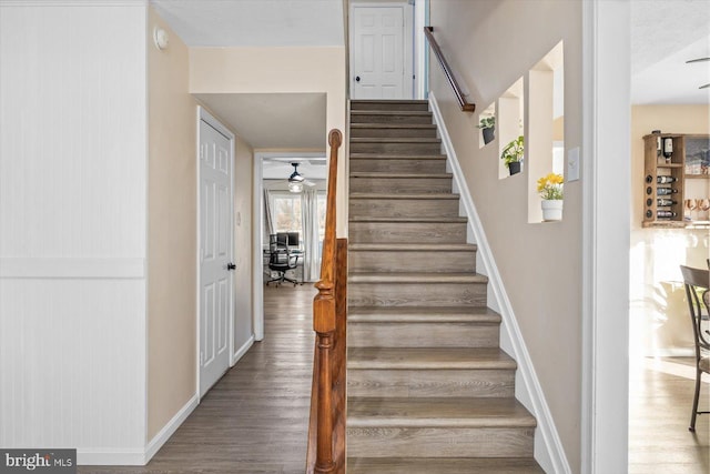 staircase with ceiling fan, wood-type flooring, and a textured ceiling