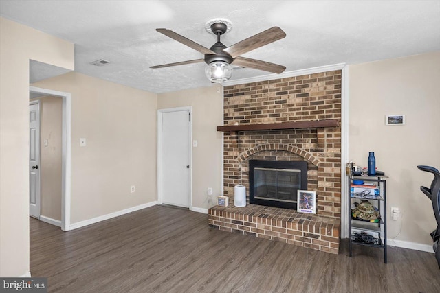 living room featuring a textured ceiling, dark hardwood / wood-style flooring, a brick fireplace, and ceiling fan