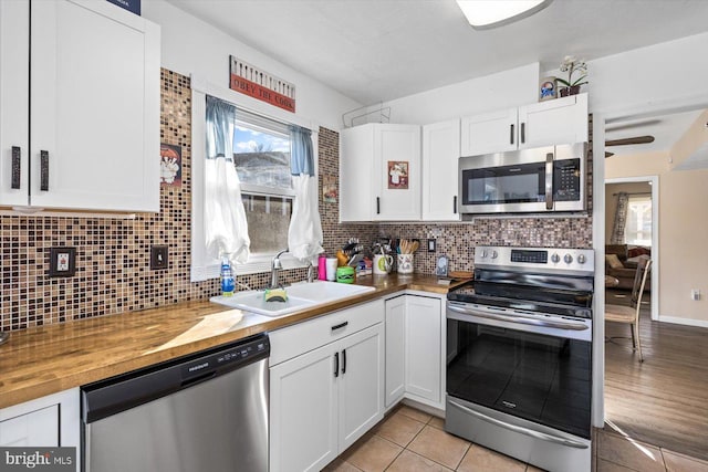 kitchen with white cabinetry, sink, wood counters, tasteful backsplash, and appliances with stainless steel finishes