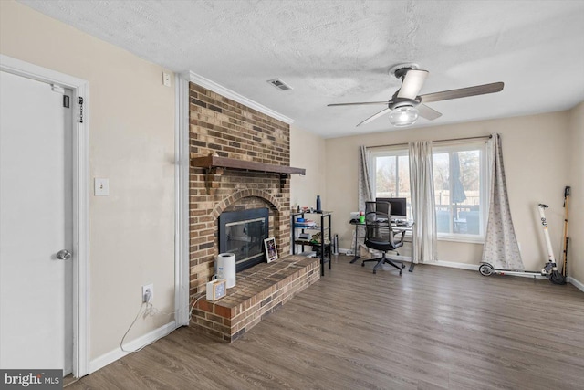 home office with a fireplace, a textured ceiling, dark hardwood / wood-style floors, and ceiling fan