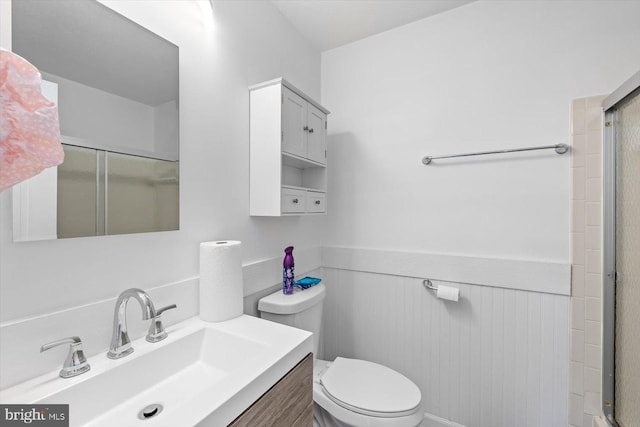 bathroom featuring vanity, toilet, and a shower with shower door