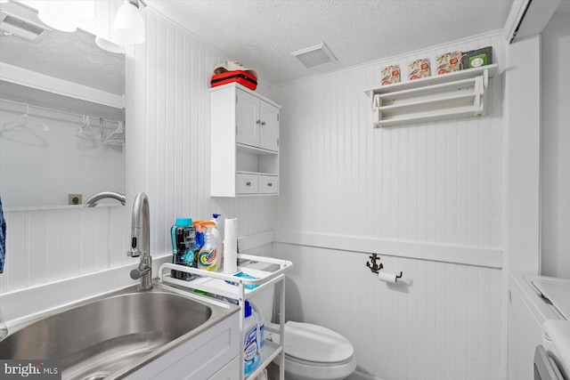 bathroom featuring a textured ceiling, toilet, and sink