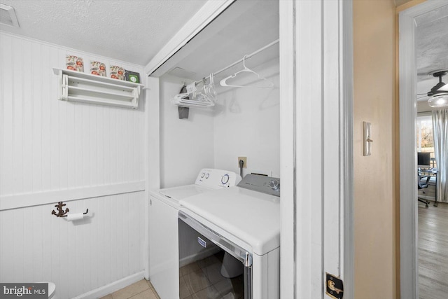 washroom featuring independent washer and dryer, a textured ceiling, wooden walls, and light hardwood / wood-style flooring