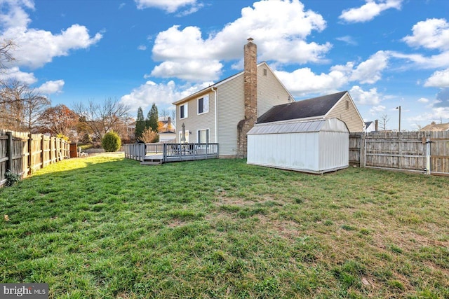 back of property featuring a lawn, a storage unit, and a wooden deck