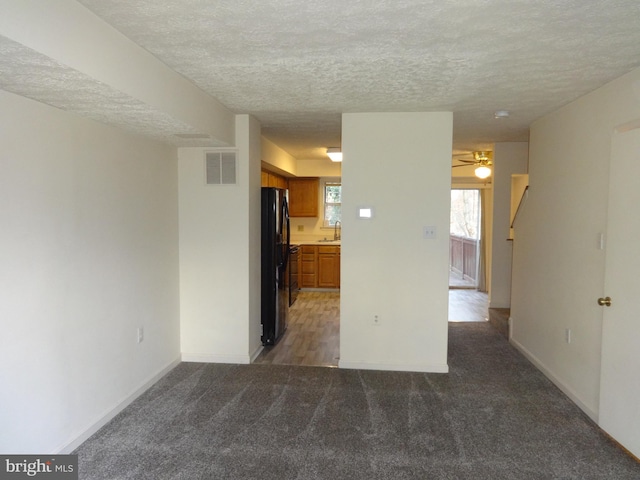 carpeted empty room featuring ceiling fan, sink, and a textured ceiling