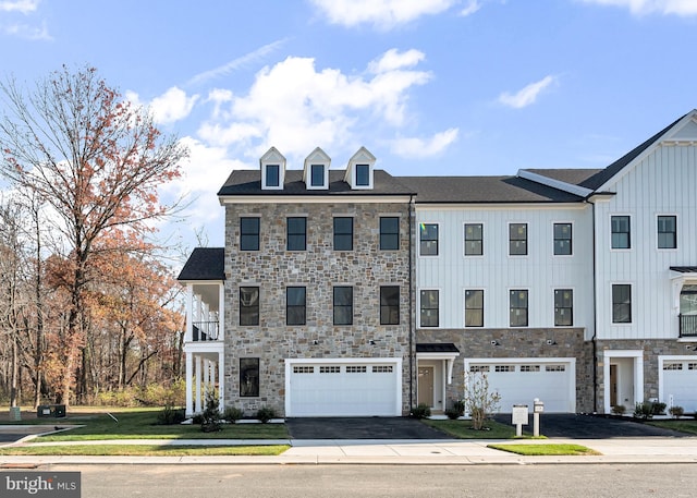 multi unit property featuring stone siding, aphalt driveway, board and batten siding, and an attached garage