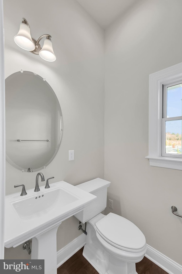 half bathroom with toilet, baseboards, and wood finished floors