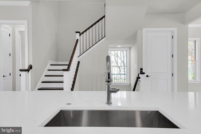 interior space featuring light countertops, ornamental molding, a sink, and baseboards