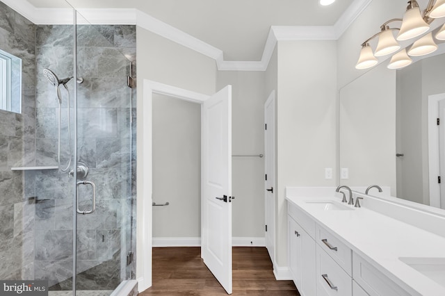 bathroom with wood finished floors, a sink, baseboards, ornamental molding, and a shower stall