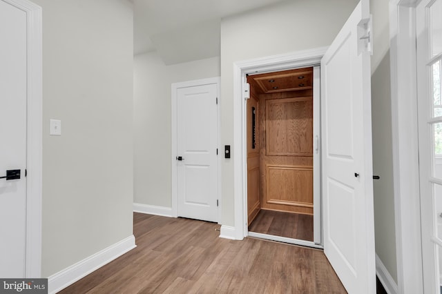 corridor with light wood-style floors and baseboards