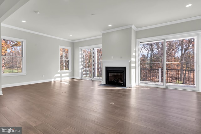 unfurnished living room with recessed lighting, a fireplace with flush hearth, wood finished floors, baseboards, and crown molding