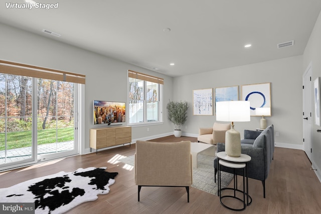 living room featuring baseboards, visible vents, wood finished floors, and recessed lighting