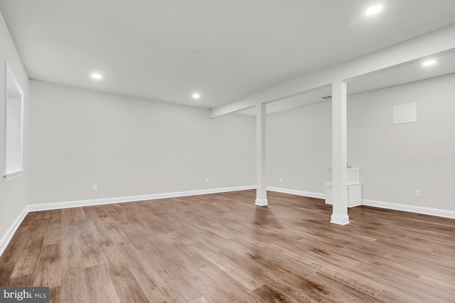 finished below grade area featuring light wood finished floors, recessed lighting, and baseboards