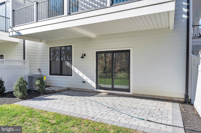 doorway to property with a balcony, fence, central AC, and a patio