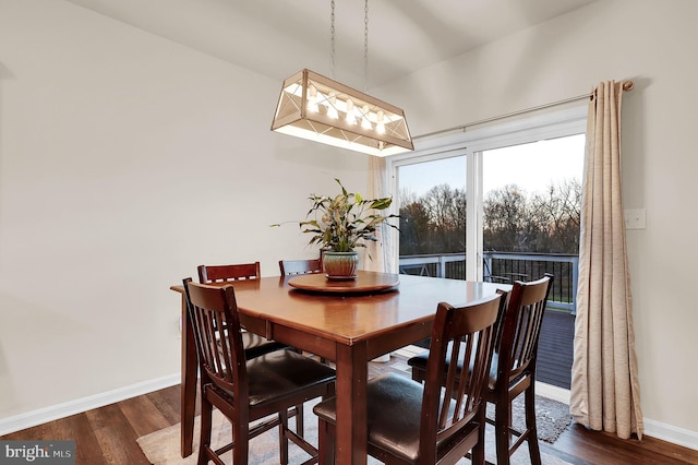 dining space with dark hardwood / wood-style flooring, lofted ceiling, and an inviting chandelier