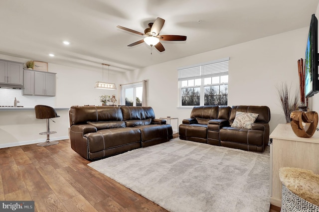 living room with hardwood / wood-style floors, ceiling fan, and sink