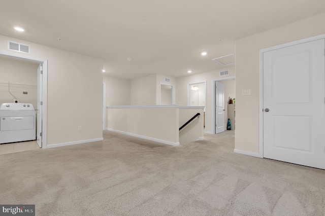 spare room with light colored carpet and washer / dryer