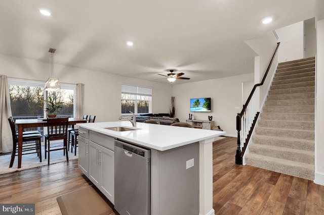 kitchen with sink, wood-type flooring, pendant lighting, a center island with sink, and dishwasher