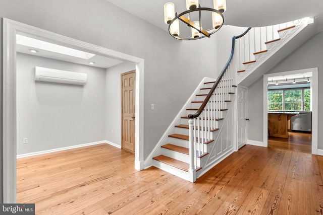 stairway with a wall unit AC, a skylight, wood-type flooring, and a notable chandelier