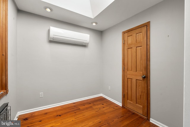 unfurnished room featuring hardwood / wood-style flooring and an AC wall unit