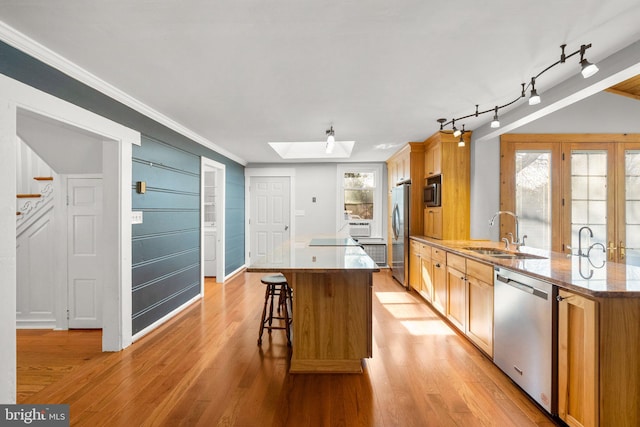 kitchen featuring light hardwood / wood-style floors, sink, stainless steel appliances, and a skylight