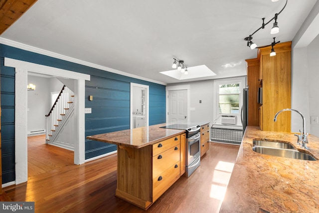 kitchen with a skylight, sink, dark hardwood / wood-style flooring, stainless steel range with electric stovetop, and a kitchen island