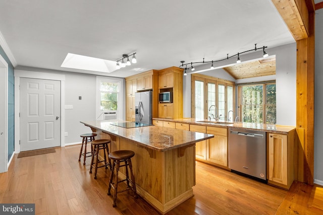 kitchen featuring light stone countertops, sink, light hardwood / wood-style floors, and appliances with stainless steel finishes