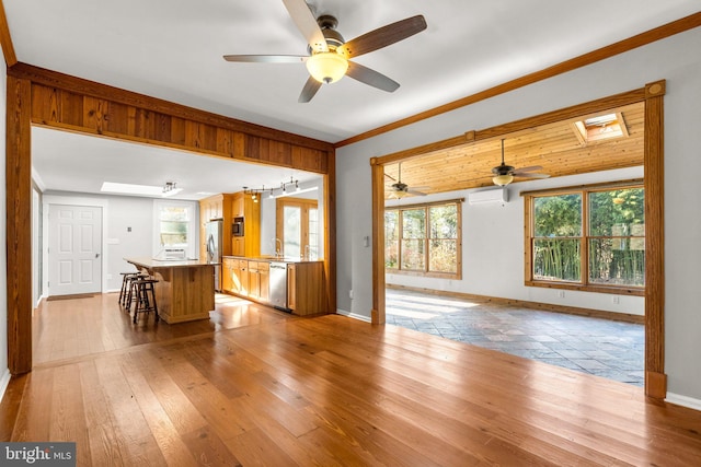 living room featuring light hardwood / wood-style flooring, a skylight, ceiling fan, ornamental molding, and a wall unit AC