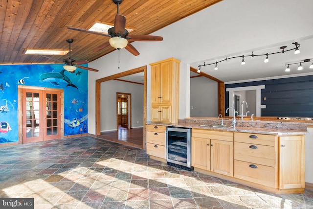 kitchen with light brown cabinets, lofted ceiling with skylight, sink, wood ceiling, and beverage cooler