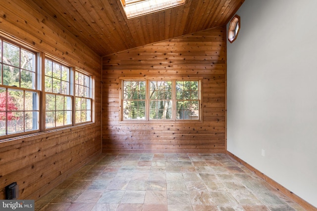 empty room with vaulted ceiling with skylight, wood ceiling, and wooden walls