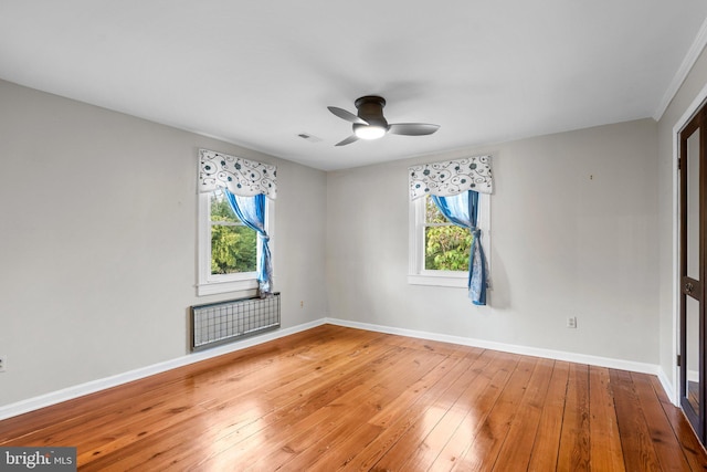 empty room featuring a wealth of natural light, hardwood / wood-style floors, and ceiling fan