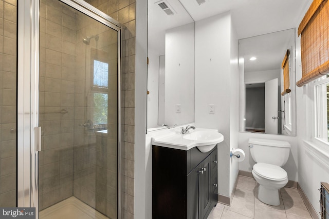 bathroom with tile patterned floors, a shower with door, vanity, and toilet