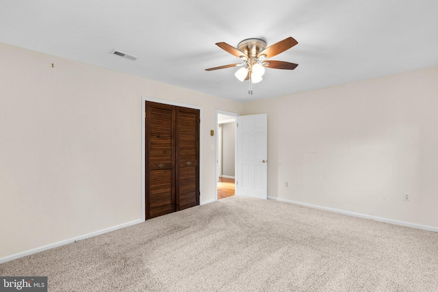 unfurnished bedroom featuring ceiling fan, light colored carpet, and a closet