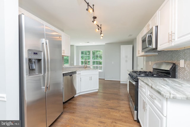 kitchen with decorative backsplash, white cabinetry, wood-type flooring, and appliances with stainless steel finishes