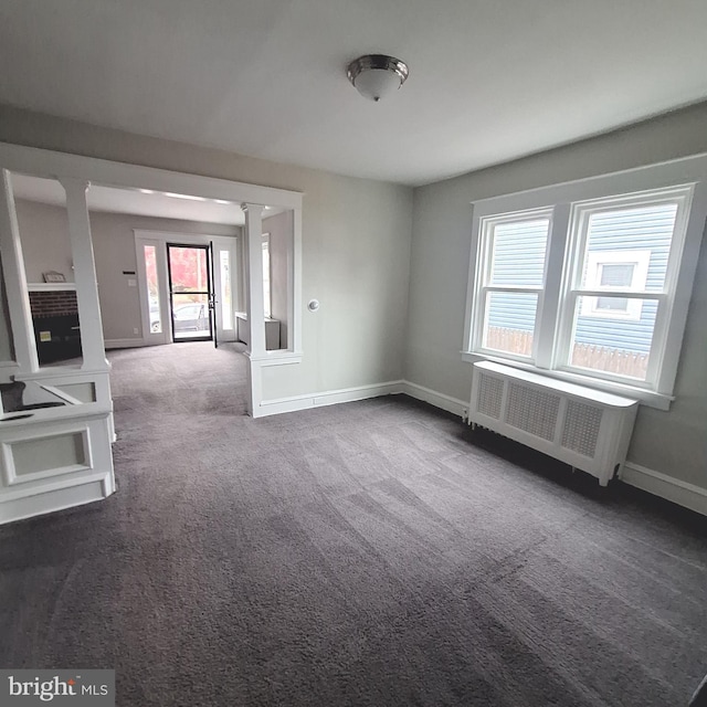 carpeted spare room featuring decorative columns, plenty of natural light, and radiator