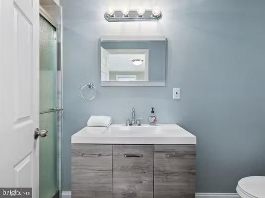 bathroom with vanity, toilet, and a shower with shower door