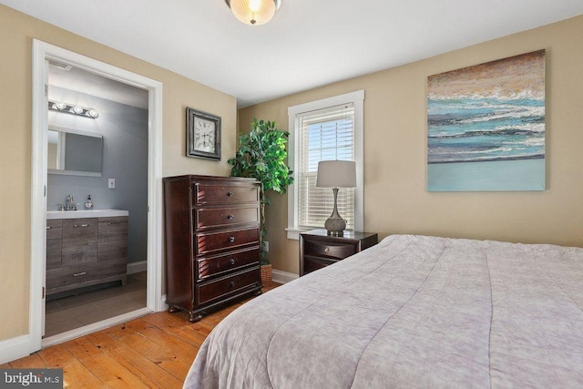 bedroom with light wood-type flooring and connected bathroom