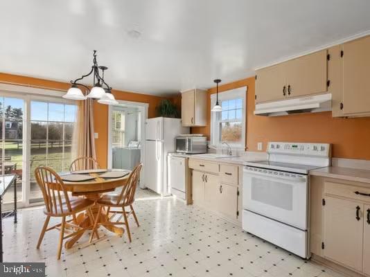 kitchen with white appliances, sink, pendant lighting, cream cabinets, and an inviting chandelier