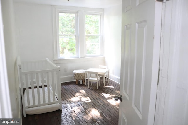 bedroom featuring wood-type flooring and a nursery area