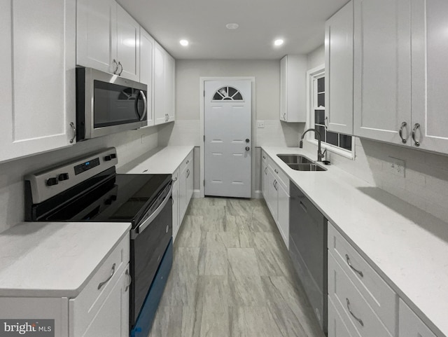 kitchen with backsplash, white cabinetry, sink, and appliances with stainless steel finishes