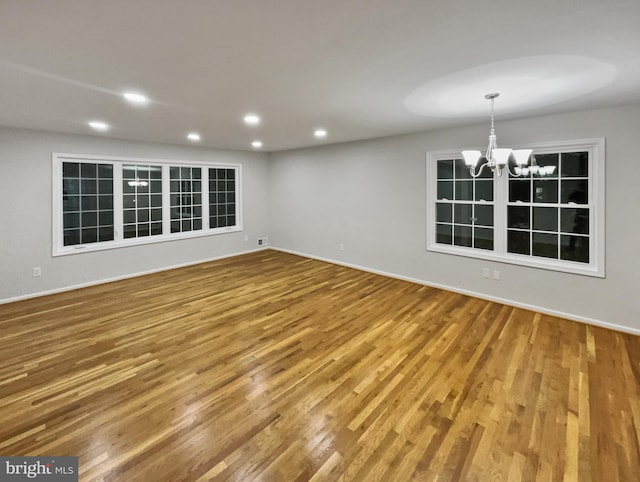 unfurnished room featuring wood-type flooring and a notable chandelier